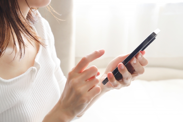 スマートフォンを指で操作する女性