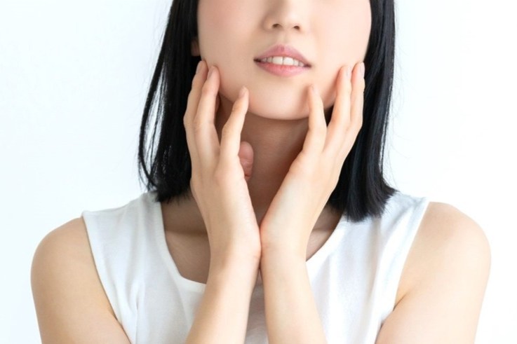 きれいな肌に両手で触れる女性