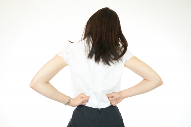 腰を押さえる女性の後ろ姿