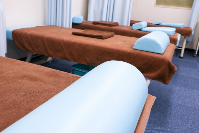 複数の施術台に茶色のタオルと水色のクッションが置かれた施術室